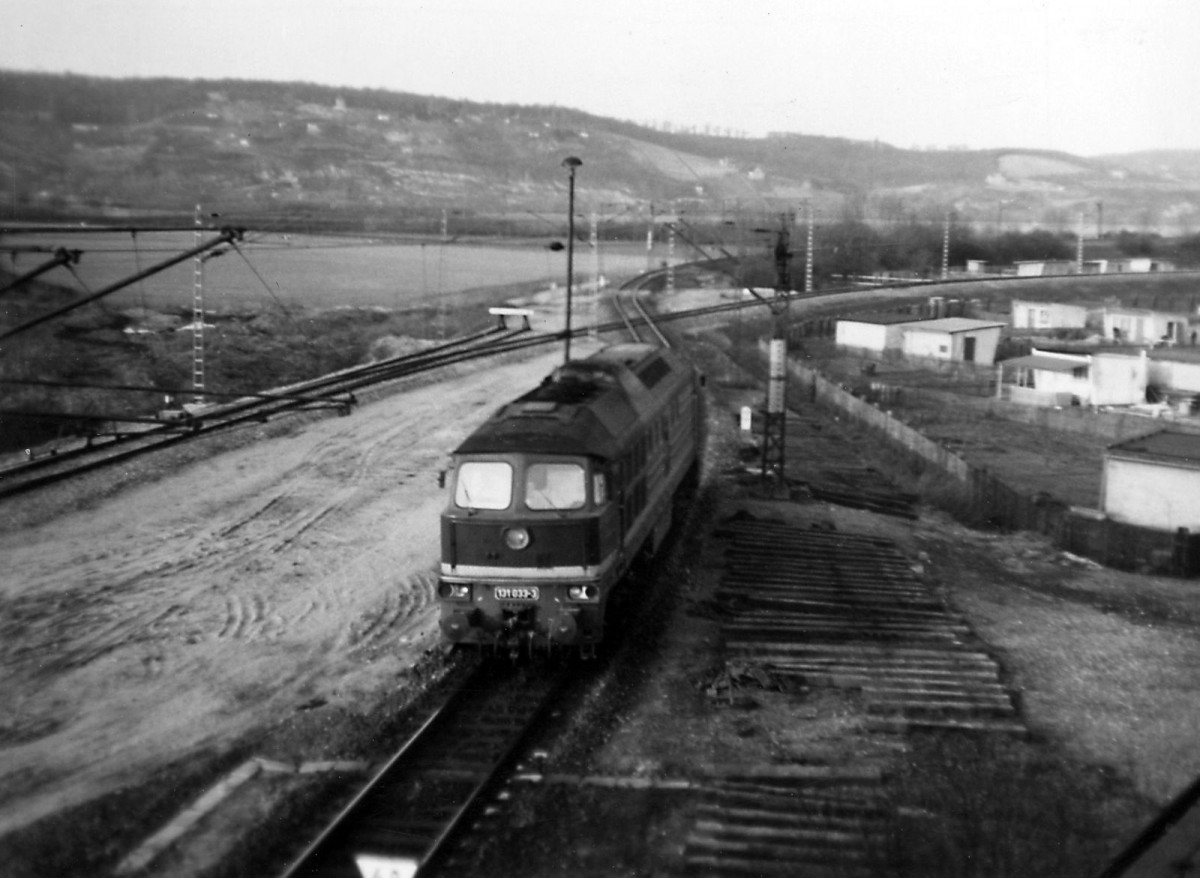 Als  Gartengleis  in Naumburg (S) Hbf wurde fr�her das Gleis 15 bezeichnet, welches Mitte/Ende der 70ger Jahre angelegt wurde, um die Aufnahmef�higkeit von G�terz�gen aus Richtung Wei�enfels in Richtung Karsdorf weiter zu erh�hen.
Schon damals hielten sich Ger�chte, das die Finanzierung/Teilfinanzierung von den Zementwerken Karsdorf erfolgte. Das Gleis zweigte hinter dem Einfahrsignal A (Strecke Wei�enfels - Naumburg) �ber die Weiche 2 ab, verlief durch besagte Gartenkolonie kreuzte die Strecke nach Naumburg Ost und Teuchern mittels Gleiskreuzung und verlief dann �ber die Weiche 15 (Schutzweiche) direkt neben der sogenannten  Panzerstra�e  bis zum Signal S 15. Ab hier waren zun�chst nur Ausfahrten auf die Unstrutbahn signalm��ig m�glich. Sollte eine Zugfahrt in Richtung Bad K�sen aus Gleis 15 stattfinden, wurde auf Stellwerk W 2 eine
Rangierfahrstra�e aus Gleis 15 nach Gleis 2 west eingestellt und auf Ersatzsignal ausgefahren. Sp�ter fand dann die signalm��ige Anbindung in diese Richtung statt. Da das Gleis 15 isoliert war (Rotausleuchtung bei Gleisbesetzung) gab es auch eine Freimeldeanlage f�r St�rungsf�lle direkt an einem Fahrleitungsmast neben Gleis 15 (Schl�sselkasten). Im Jahr 1977 sieht man diese Gleiskreuzung hinter der DR 131 033-3. (Text und Fotos: Roland Reimer)